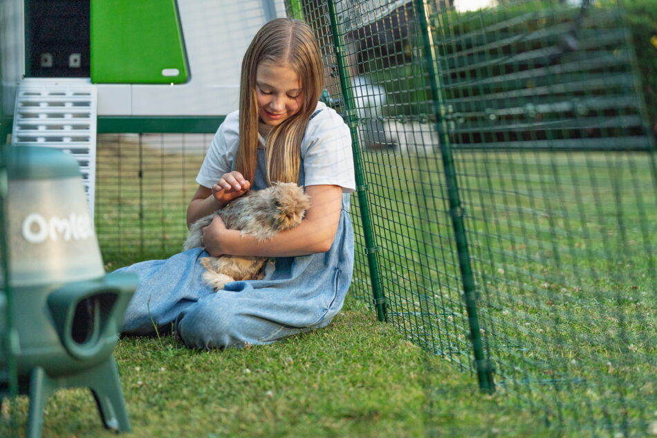 Bambina con il mano una gallina nel recinto di Eglu Cube di Omlet