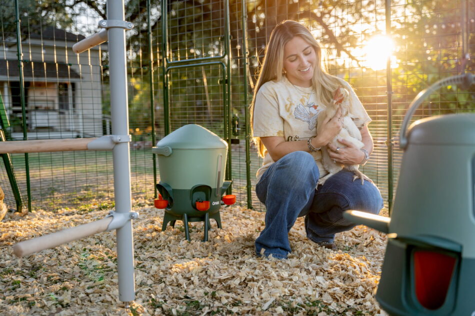 Donna con una gallina in braccio nel recinto Walk-In di Omlet