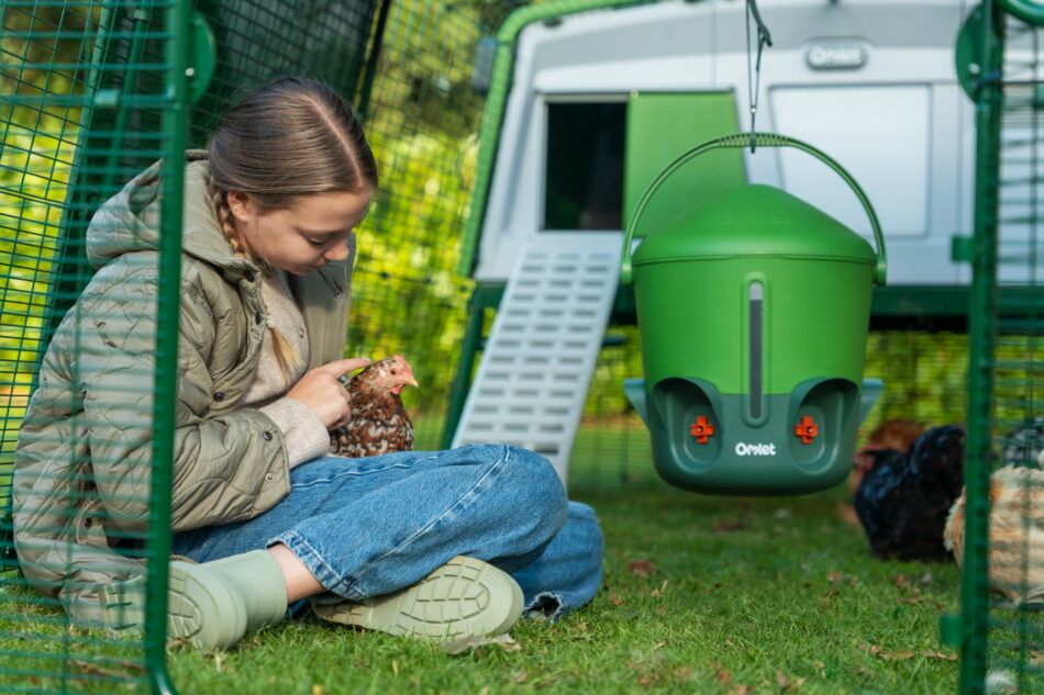 bambina con in mano una gallina di fronte a un pollaio eglu pro