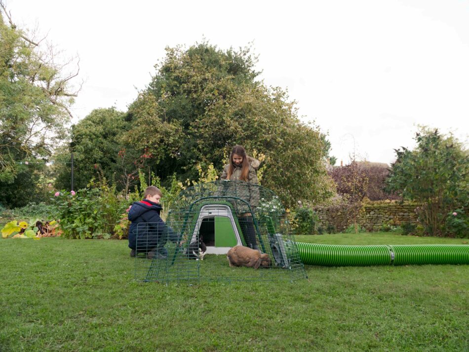 Bambini in un giardino in inverno con dei conigli nella loro casetta Eglu Go di Omlet