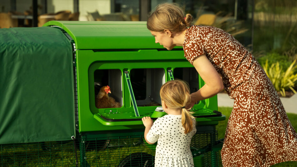 Donna e bambina che guardano una gallina nel nido di Eglu Pro